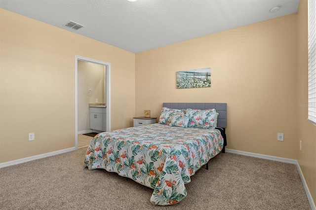 carpeted bedroom with a textured ceiling and ensuite bath