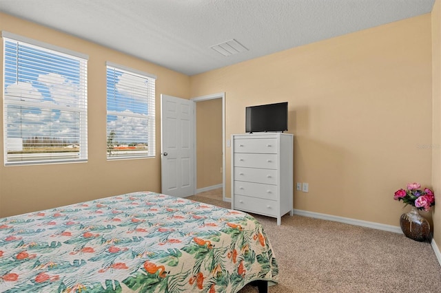 bedroom with light colored carpet and a textured ceiling