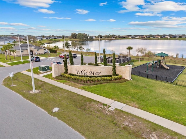 community sign featuring a water view and a yard