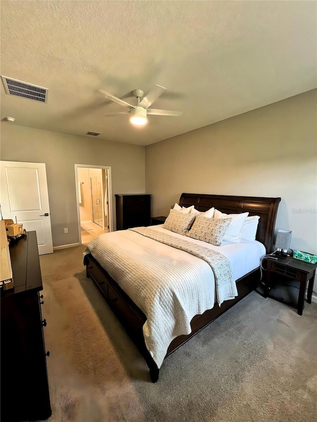 bedroom featuring ceiling fan, ensuite bathroom, a textured ceiling, and carpet flooring