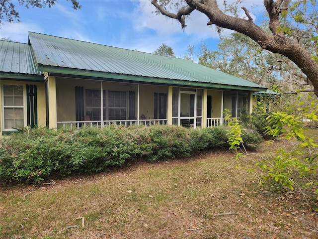 view of side of property featuring metal roof and a sunroom