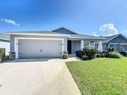 ranch-style home featuring driveway, an attached garage, and a front lawn