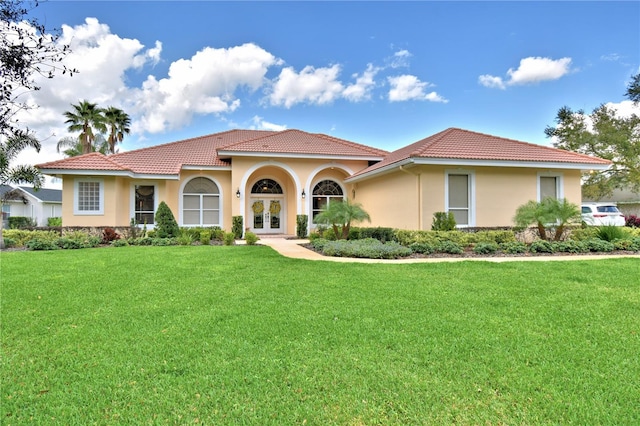 mediterranean / spanish-style home with a front yard and french doors