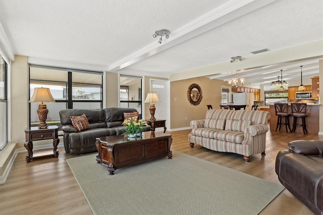 living room featuring hardwood / wood-style flooring, beamed ceiling, a textured ceiling, and a notable chandelier