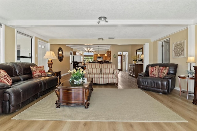 living room with beamed ceiling, an inviting chandelier, a textured ceiling, and light hardwood / wood-style flooring