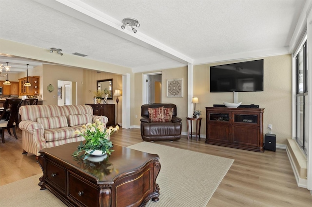 living room featuring light hardwood / wood-style flooring, beamed ceiling, and a textured ceiling