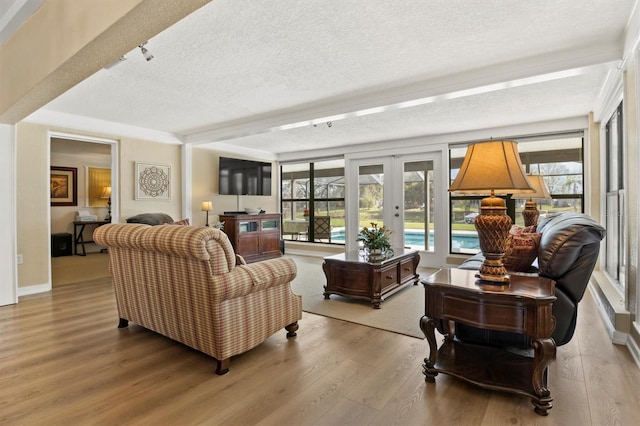 living room with a textured ceiling, light wood-type flooring, and french doors