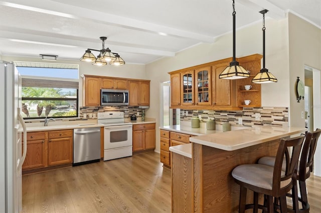 kitchen with appliances with stainless steel finishes, hanging light fixtures, light hardwood / wood-style floors, kitchen peninsula, and beamed ceiling