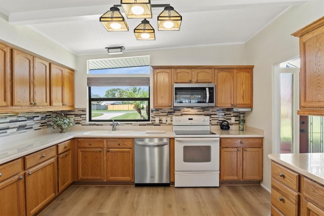 kitchen featuring appliances with stainless steel finishes, decorative light fixtures, sink, and light wood-type flooring