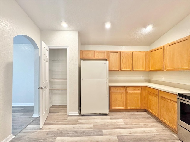 kitchen with electric stove, light hardwood / wood-style floors, and white fridge