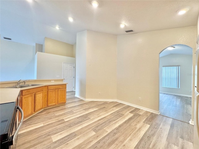 interior space featuring lofted ceiling, sink, light hardwood / wood-style flooring, and electric range