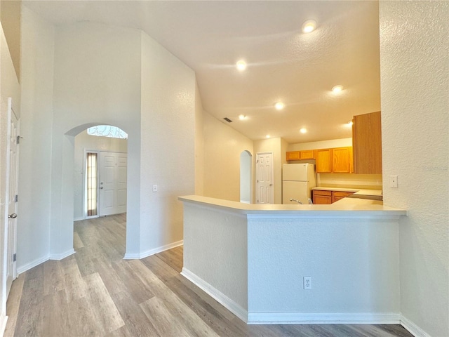 kitchen featuring white refrigerator, kitchen peninsula, and light hardwood / wood-style flooring