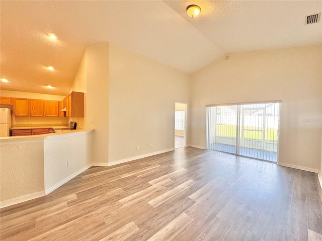 unfurnished living room with high vaulted ceiling and light hardwood / wood-style floors