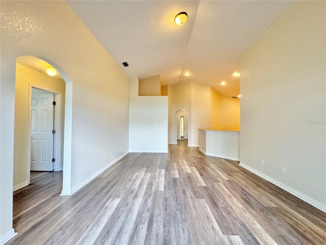 unfurnished living room featuring hardwood / wood-style flooring, lofted ceiling, and a textured ceiling