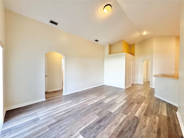 spare room featuring hardwood / wood-style floors, a textured ceiling, and high vaulted ceiling