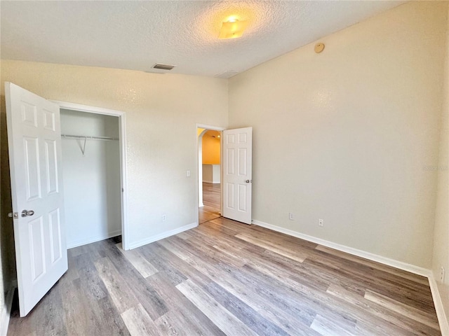 unfurnished bedroom with light hardwood / wood-style flooring, a closet, and a textured ceiling