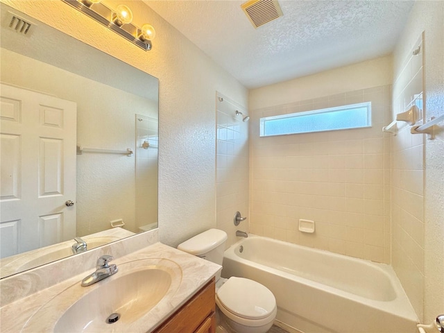 full bathroom featuring tiled shower / bath, vanity, a textured ceiling, and toilet