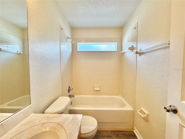 full bathroom with wood-type flooring, tiled shower / bath combo, vanity, toilet, and a textured ceiling