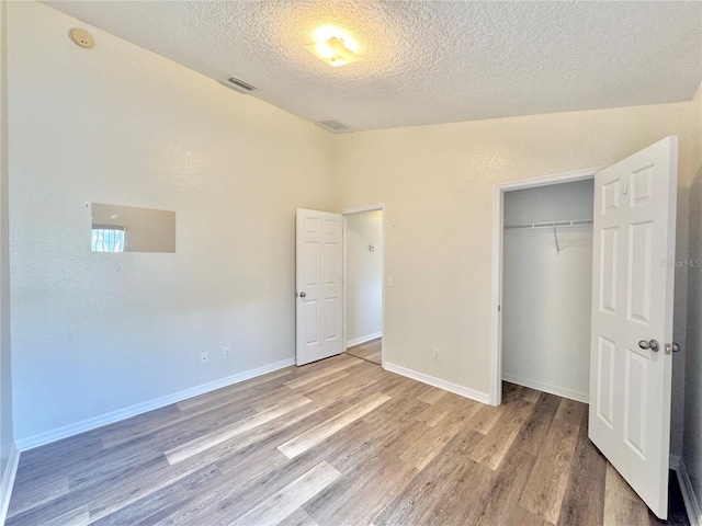 unfurnished bedroom with hardwood / wood-style flooring, a closet, and a textured ceiling