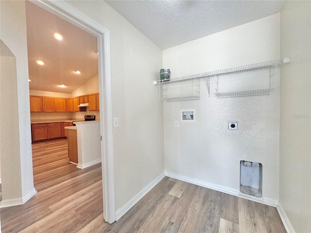 washroom with washer hookup, hookup for an electric dryer, light hardwood / wood-style flooring, and a textured ceiling