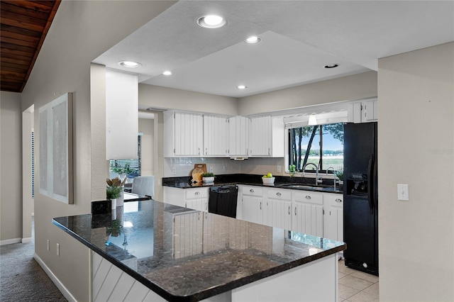 kitchen with white cabinets, a sink, a peninsula, and black appliances