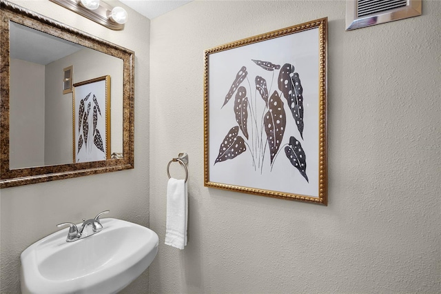 bathroom featuring a sink, a textured wall, a wall mounted AC, and visible vents