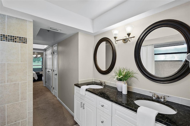 ensuite bathroom with a sink, ensuite bathroom, a chandelier, and visible vents