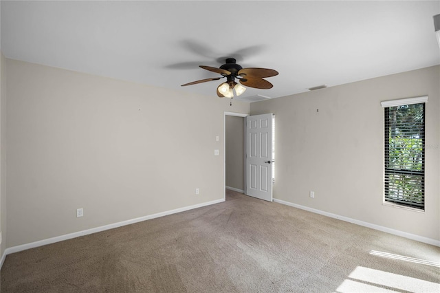 carpeted empty room featuring baseboards, visible vents, and a ceiling fan