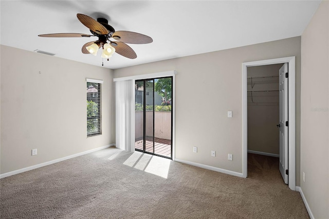 unfurnished bedroom featuring access to exterior, carpet floors, a walk in closet, baseboards, and visible vents
