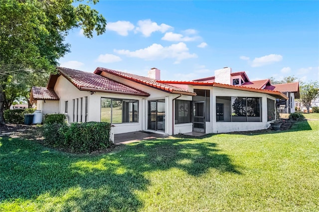back of property featuring stucco siding, a sunroom, a tiled roof, and a yard