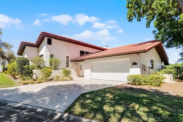 view of front of property with a tile roof, stucco siding, a garage, and driveway
