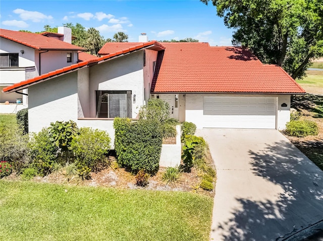 mediterranean / spanish home with stucco siding, an attached garage, a tiled roof, and concrete driveway