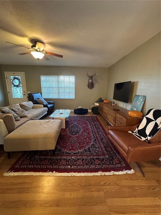 living area featuring a textured ceiling, wood finished floors, and a ceiling fan