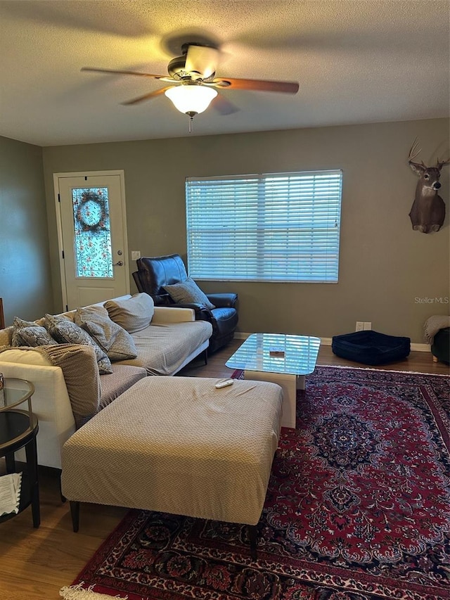 living room featuring a ceiling fan, a textured ceiling, and wood finished floors