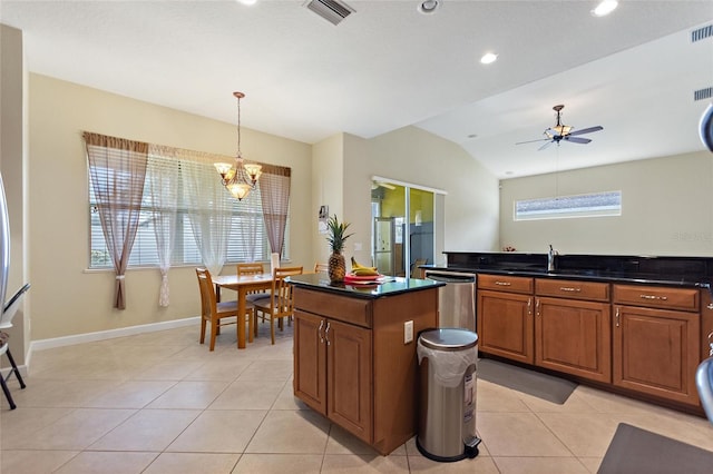 kitchen with light tile patterned flooring, sink, decorative light fixtures, vaulted ceiling, and stainless steel dishwasher