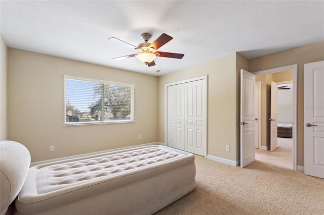 carpeted bedroom with ceiling fan, a closet, and a textured ceiling