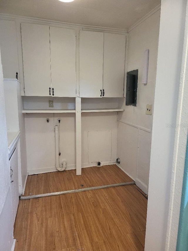 laundry room featuring cabinets, electric panel, and light hardwood / wood-style flooring