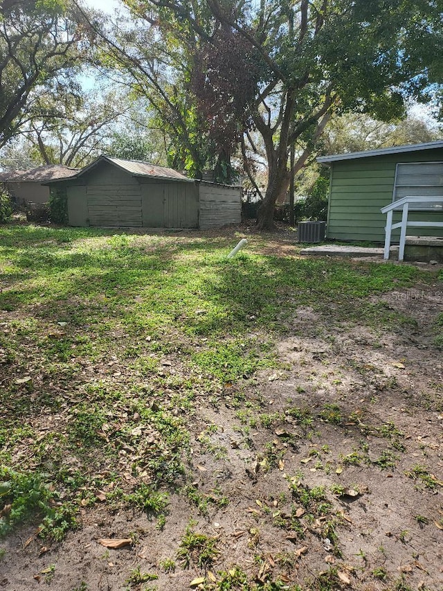 view of yard featuring central AC and a storage unit