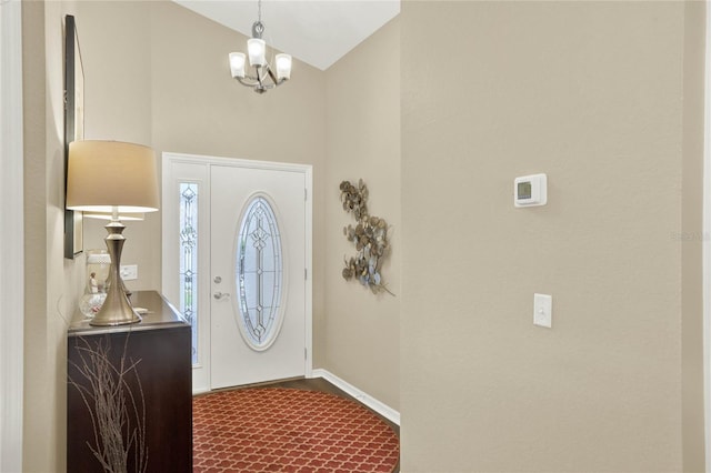 carpeted foyer entrance with lofted ceiling and a notable chandelier