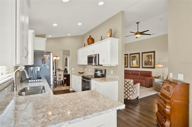 kitchen with lofted ceiling, sink, light stone counters, white cabinetry, and stainless steel appliances