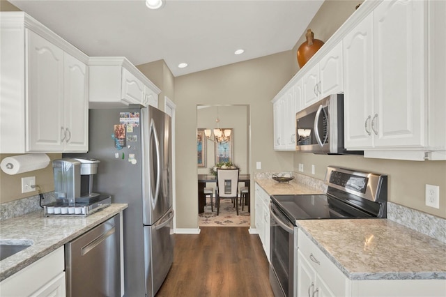 kitchen featuring appliances with stainless steel finishes, white cabinetry, dark wood-type flooring, and light stone countertops