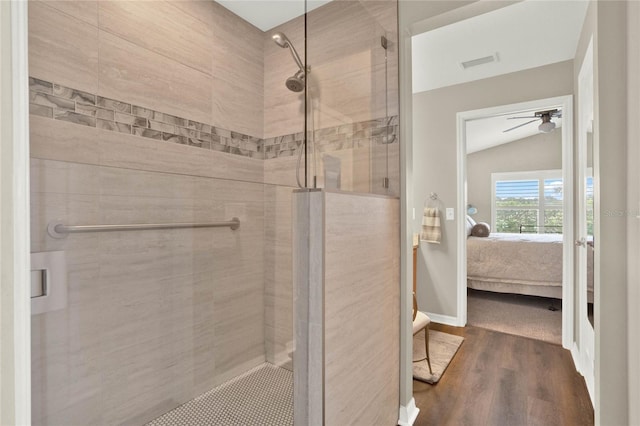 bathroom featuring hardwood / wood-style flooring, ceiling fan, a shower with door, and lofted ceiling