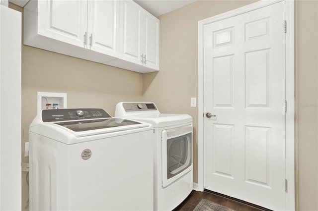 laundry room with washing machine and dryer, dark wood-type flooring, and cabinets