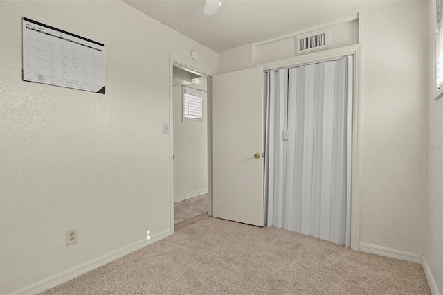 unfurnished bedroom featuring light colored carpet, ceiling fan, and a closet