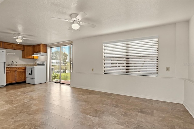 interior space with a textured ceiling, a sink, a ceiling fan, and baseboards