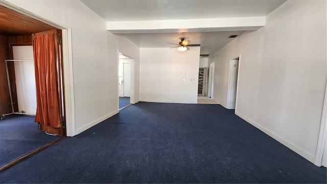 unfurnished room with beam ceiling, ceiling fan, and dark carpet