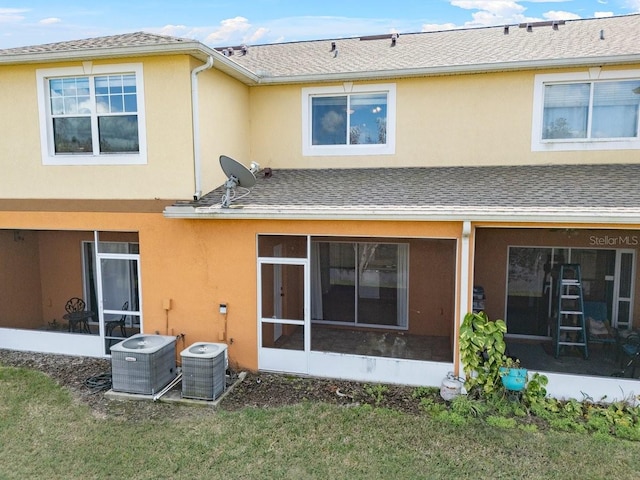 back of house featuring a lawn, a sunroom, and central air condition unit