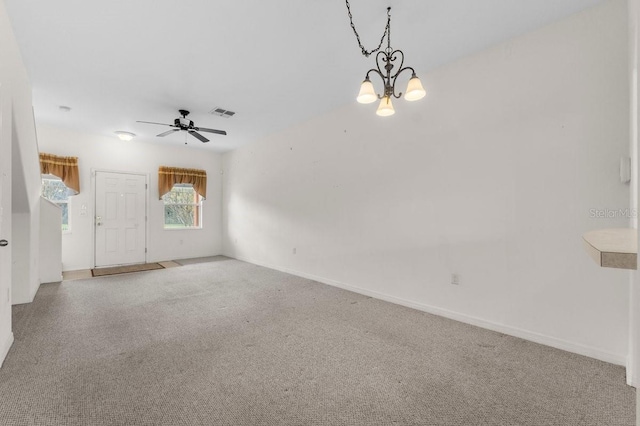 carpeted empty room featuring ceiling fan with notable chandelier