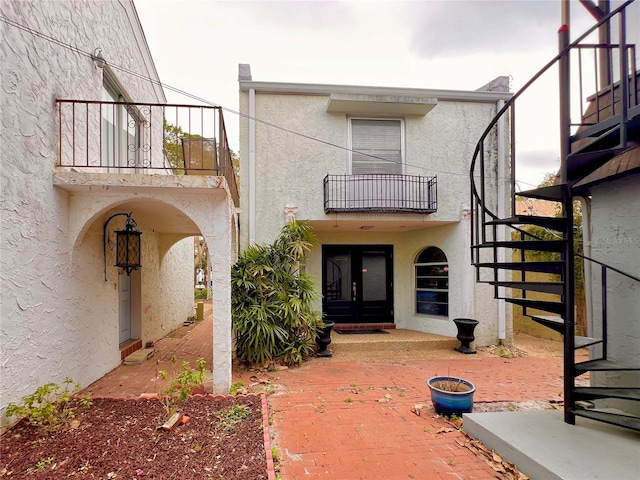 view of exterior entry featuring french doors and a balcony