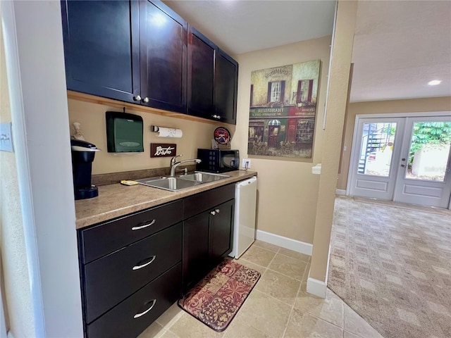 kitchen with light carpet, sink, and white dishwasher